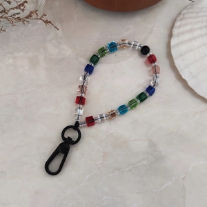 Colorful cube crystal bead keychain with black matte spring clip on marble background