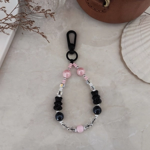 Cute beaded bear keychain with pink and black beads on a minimalist marble surface