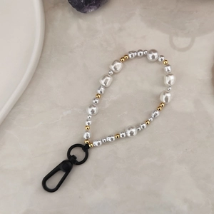 Porte-clés minimaliste en perles blanches et accents dorés sur fond de marbre
