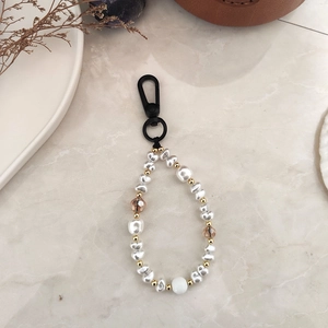 Handmade faux pearl keychain with crystal beads and gold metal spacers on marble surface