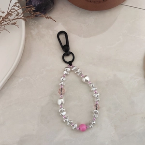 Detail view of handmade beaded keychain with baroque pearls and pink crystals on marble table