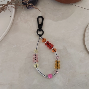 Détail des breloques ours colorées et perles étoilées sur une lanière porte-clés