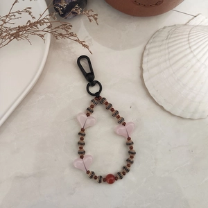 Close-up of heart-shaped beads and striped acrylic charms on an aesthetic beaded keychain
