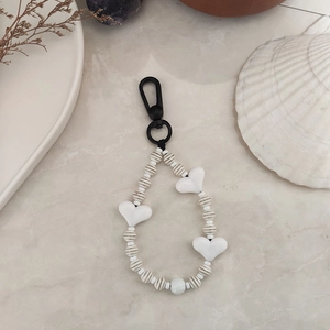 Detail shot of black and white striped acrylic beads with heart charm on marble surface