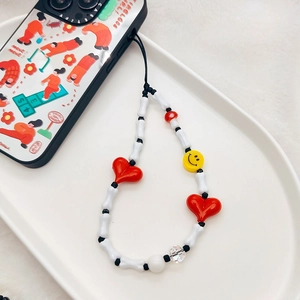 Beaded phone strap with heart, bone, and smiley face charms on white ceramic plate