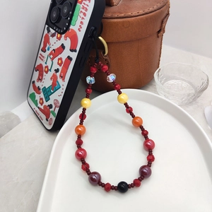 Handmade colorful beaded phone strap with trendy cartoon case on a clean ceramic plate
