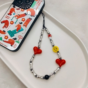 Detailed close-up of beaded phone strap with silver bones, red hearts, and smiley faces