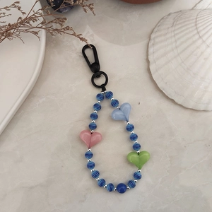 Close-up of handmade beaded keychain with blue striped beads and heart charms