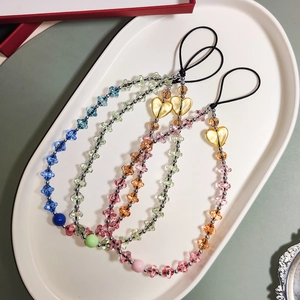 Detailed view of four colorful acrylic star and heart beaded phone straps on a tray