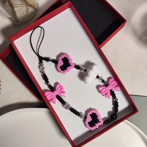 Detailansicht der rosa Herz- und Schleifenanhänger mit bunten Perlen an einem Handyband
