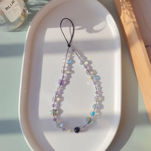Detailed macro view of purple beaded phone strap with crystal heart on white tray
