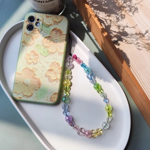Floral embossed phone case with colorful acrylic heart bead wrist strap on white tray