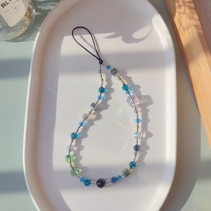 Close-up of colorful crystal beaded phone strap with butterfly heart charms on a tray