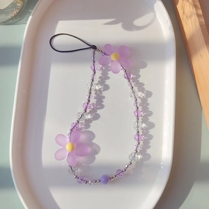 Macro shot of purple beaded phone strap with frosted flowers on a ceramic tray