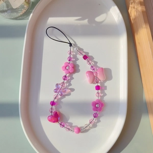 Detailed view of pink beaded phone strap with resin butterfly and crystal heart