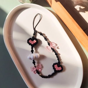 Handmade pixel heart phone charm with pink butterfly and black beads on white tray
