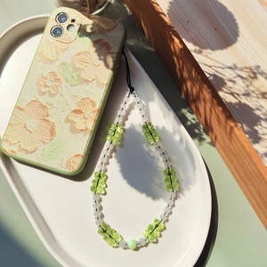 Close-up of green gummy bear beads and white pearls on floral embossed phone case