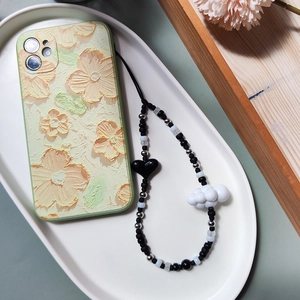 Floral relief phone case with black and white beaded heart and cloud charm strap