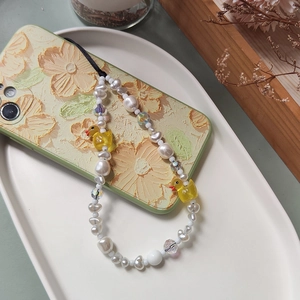 Handmade phone strap with yellow duck pendants and imitation pearls on a floral case
