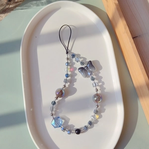 Detail of beaded phone strap with blue crystal and butterfly charm in natural sunlight