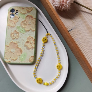 Detailed view of handmade beaded phone strap with yellow smiley faces and floral case