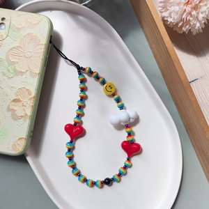 Colorful beaded phone strap with heart, smile, and cloud charms on a white tray