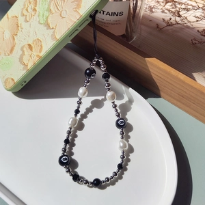 Beaded phone charm featuring billiard number 8 and baroque pearls on a floral phone case
