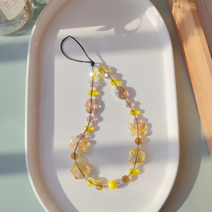 Detailed macro of amber crystal beaded phone charm with a faceted butterfly pendant