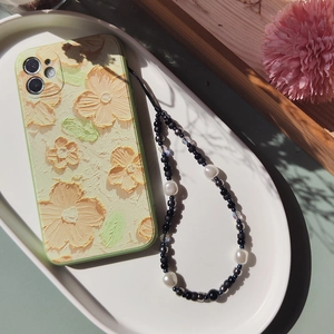 Dettaglio custodia telefono con fiori a olio e cinturino in perle e metallo