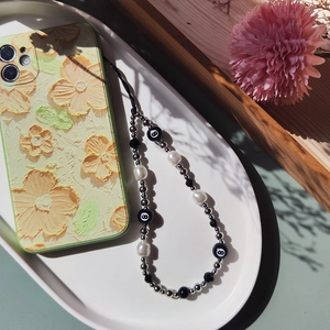 Detail of floral texture phone case with pearl and number 8 billiard bead charm