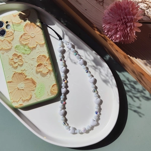 Beaded heart phone charm strap with iridescent crystals on floral embossed phone case