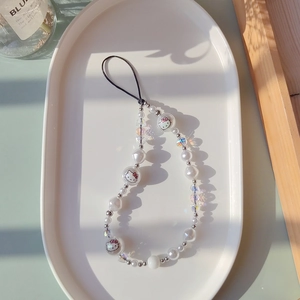 Detailed view of beaded phone strap with Hello Kitty pearls in a white ceramic tray