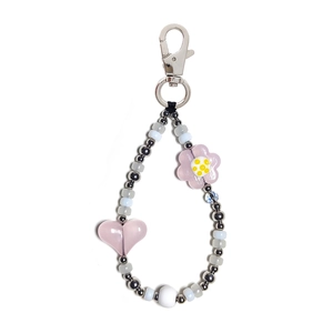 Detail of beaded keychain with pink heart, blue beads and silver floral accents for bag