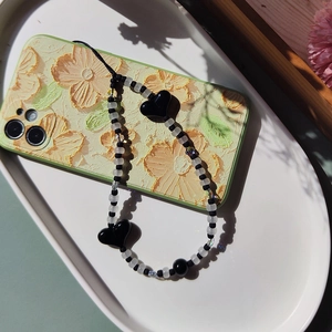 Handmade black and white beaded phone charm with heart pendants on a floral phone case
