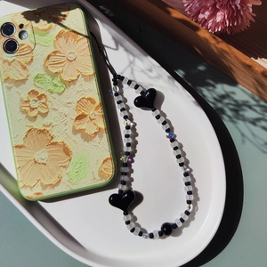 Detailed view of yellow floral embossed phone case with black and white heart beaded strap