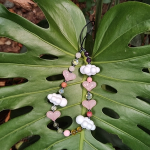 Handmade beaded phone strap with pink heart and white cloud beads on a green leaf