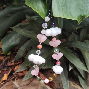 Beaded phone charm with white cloud and pink heart natural stone on green plant background
