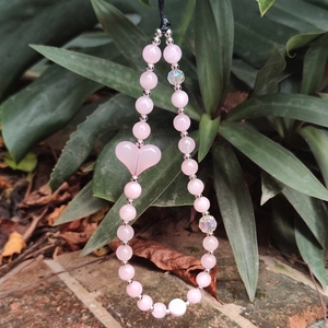 Pink crystal beaded phone strap with a heart pendant on a green succulent background