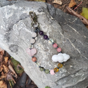 Detailed view of handmade stone heart keychain with colorful beads on a gray rock surface