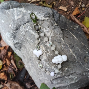 Macro shot of handmade beaded keychain with heart and cloud pendants on natural grey stone