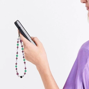 Detailed shot of handmade purple crystal and green beaded phone charm strap on a case