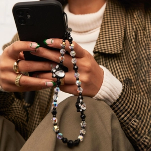Handmade beaded phone strap with black beads, crystals and decorative bows worn by a model
