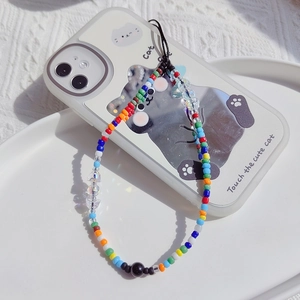 Detail of colorful beaded phone strap with resin charms on white textured background
