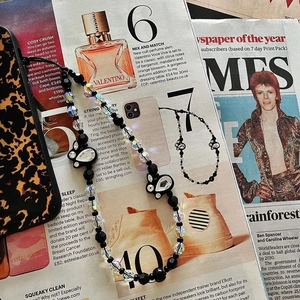 Detail of beaded phone strap with black rabbit pendant and crystals on fashion magazines