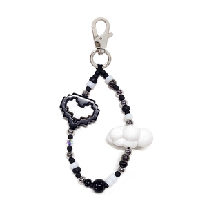 Detail of beaded keychain with pixel heart and cloud charms on a white background