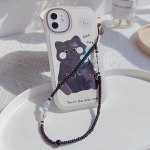 Detail of hand-painted black cat phone case with a beaded wrist strap on a white tray