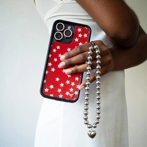 Detail of red star iPhone case featuring silver beaded strap and metal heart charm pendant