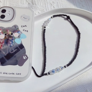 Detail shot of a beaded phone strap with black beads and a cartoon cat phone case