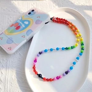 Detail of colorful rainbow beaded phone strap with multifaceted transparent beads in a tray
