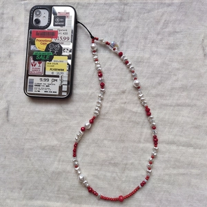 Dettaglio del cinturino per cellulare con perle barocche e rosse su custodia retro